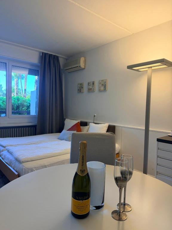 a room with a bottle of wine and glasses on a table at Holiday on The Lake Lugano 2 in Bissone