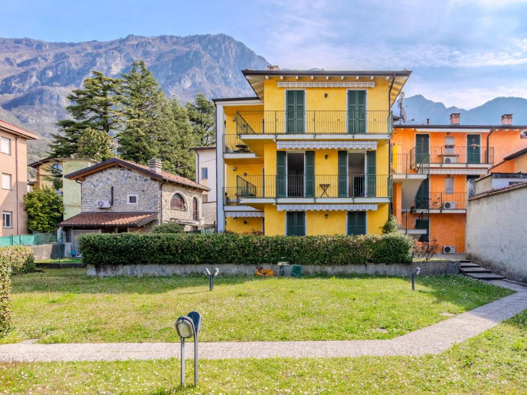 a yellow house in a yard with mountains in the background at Apartment di Lalla by Interhome in Lierna