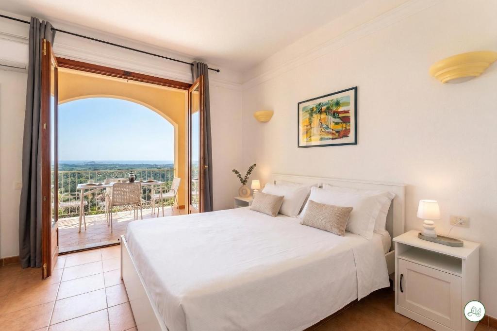 a bedroom with a white bed and a large window at Luce di Mare, Vista Mare Sea View in Is Molas 