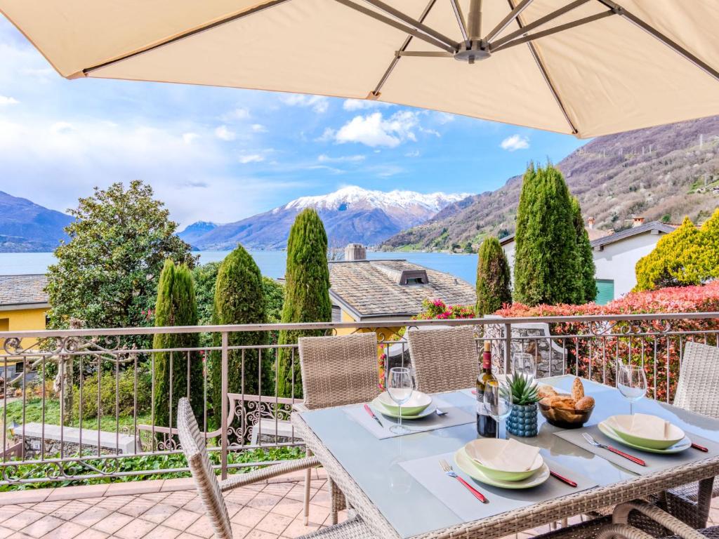 a table with an umbrella on a balcony with mountains at Apartment Onda Blu by Interhome in Gera Lario