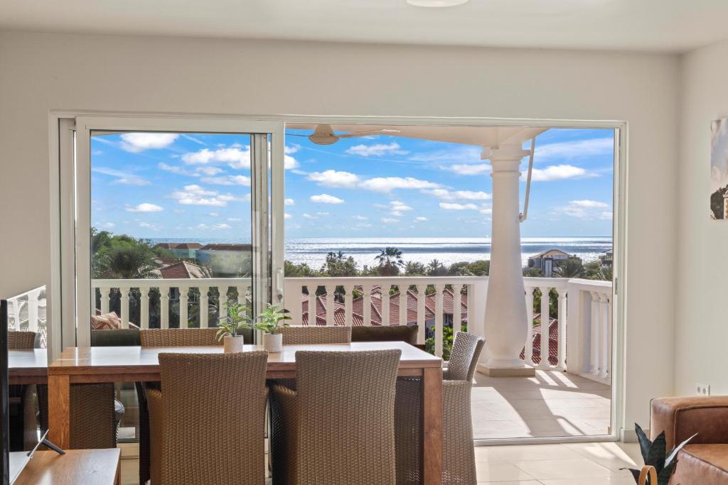 a dining room with a table and a view of a balcony at Blue Bay Apartments in Dorp Sint Michiel