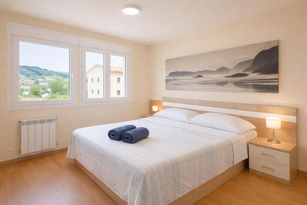 a bedroom with a large white bed with two windows at Nova MSuites Catedrales in Foz