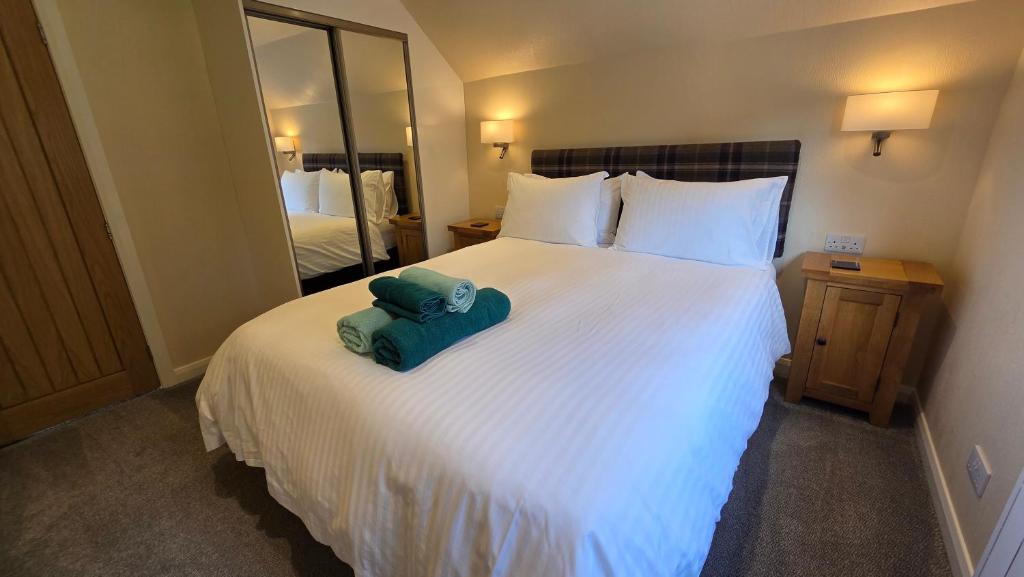 a bedroom with a large white bed with a towel on it at Bunroy Park in Fort William
