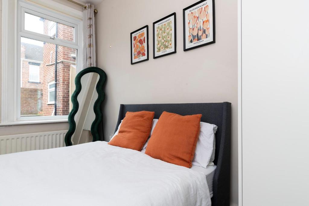 a bedroom with a bed with orange pillows and a window at Bright & Comfortable 2-Bed Home 5 mins from Newcastle City Centre - Free Parking in Gateshead