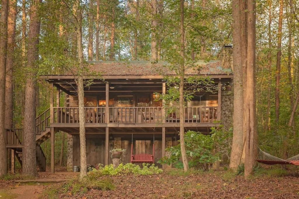 a tree house with a deck in the woods at The Pines Riverside Log Cabin On The Ocoee in Ocoee