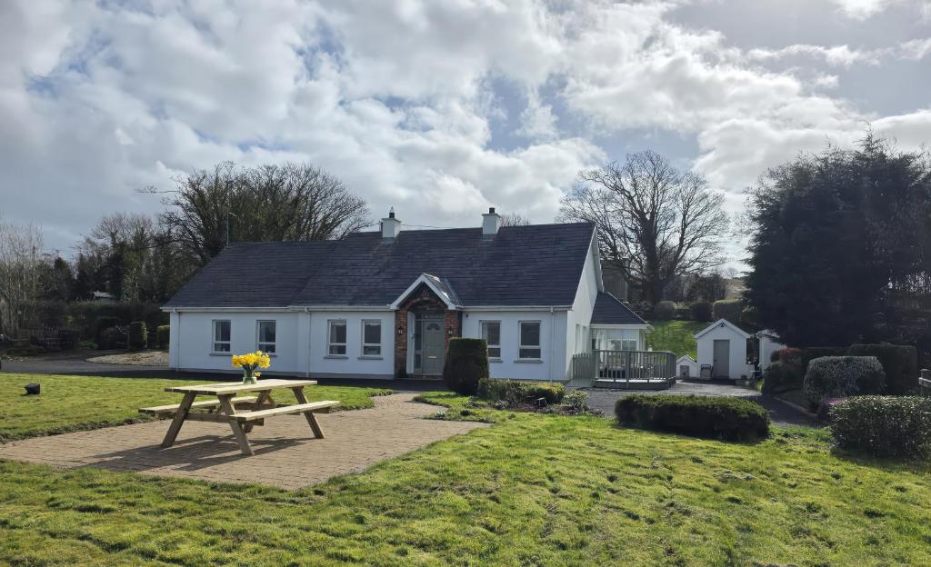 a white house with a picnic table in the yard at An Grianán Getaway in Burt