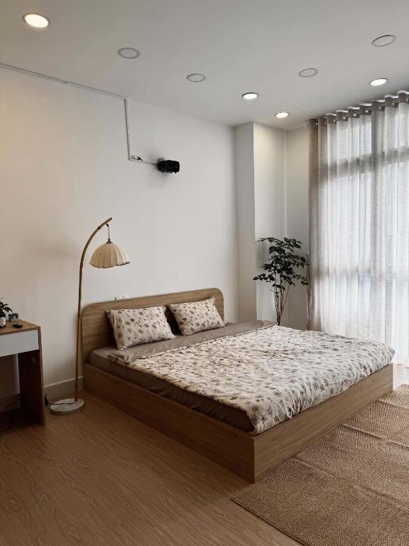 a bedroom with a large bed and a lamp at Ceilé Stay Đà Lạt in Da Lat