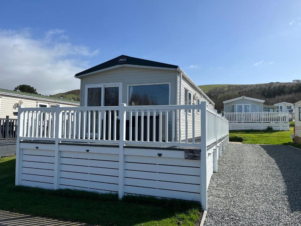 a small white building with a gate on the grass at 8 Puffin Way in Llwyngwril