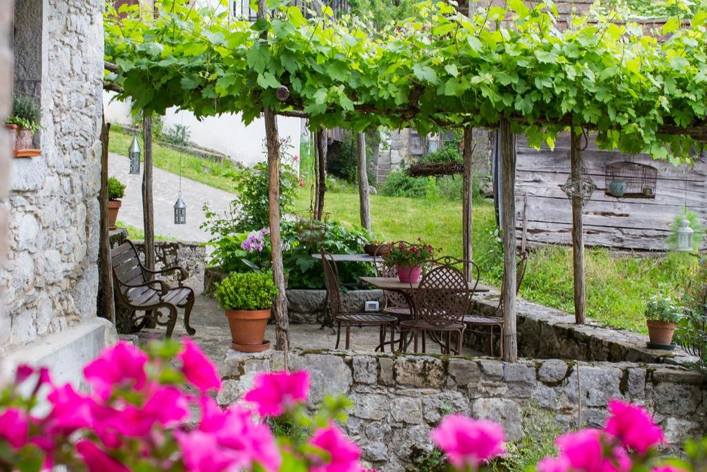 een patio met een tafel, stoelen en bloemen bij Casa Sittaro in Grimacco