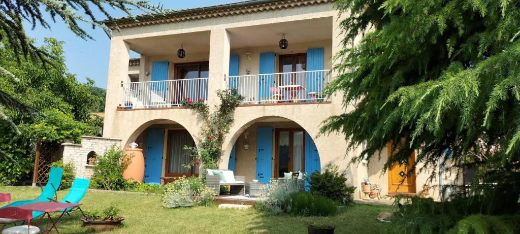 a house with blue doors and chairs in a yard at Chambre D'hôtes La Grande Calade in Lagrand