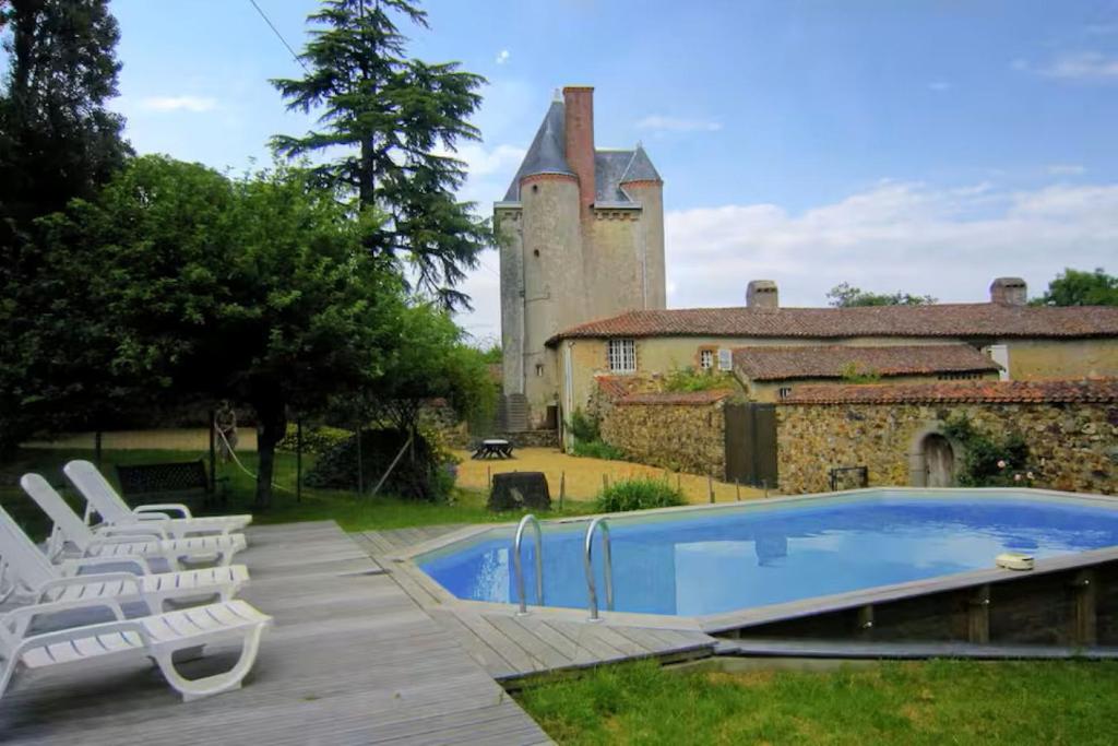a swimming pool in front of a building with a castle at La Gaubertière in Saint-Paul-du-Bois