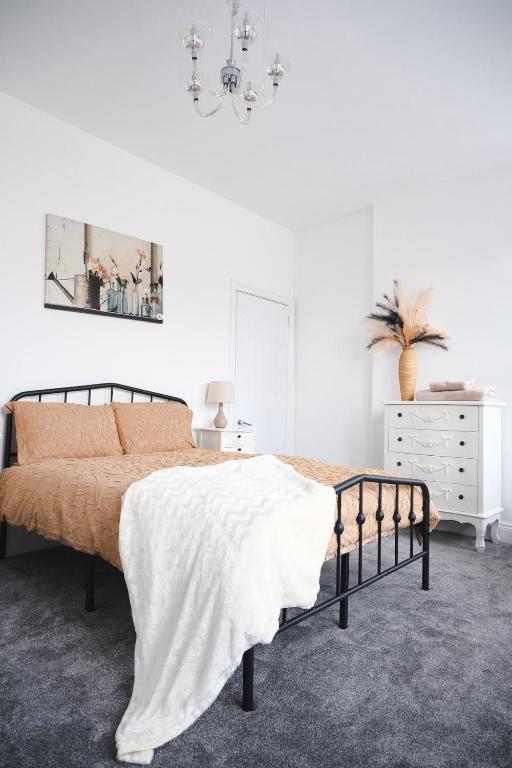 a white bedroom with a bed and a dresser at Sunrise Properties in Barnstaple