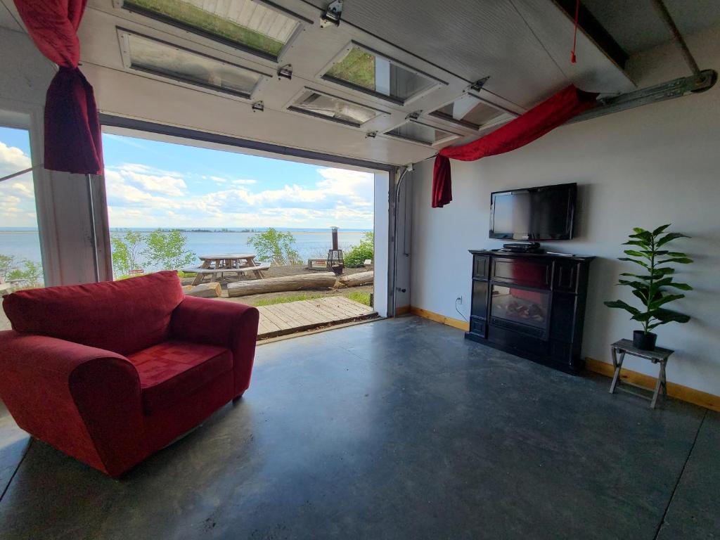 a living room with a red chair and a fireplace at Aux 4 vents - Auberg'Inn in Carleton-sur-Mer