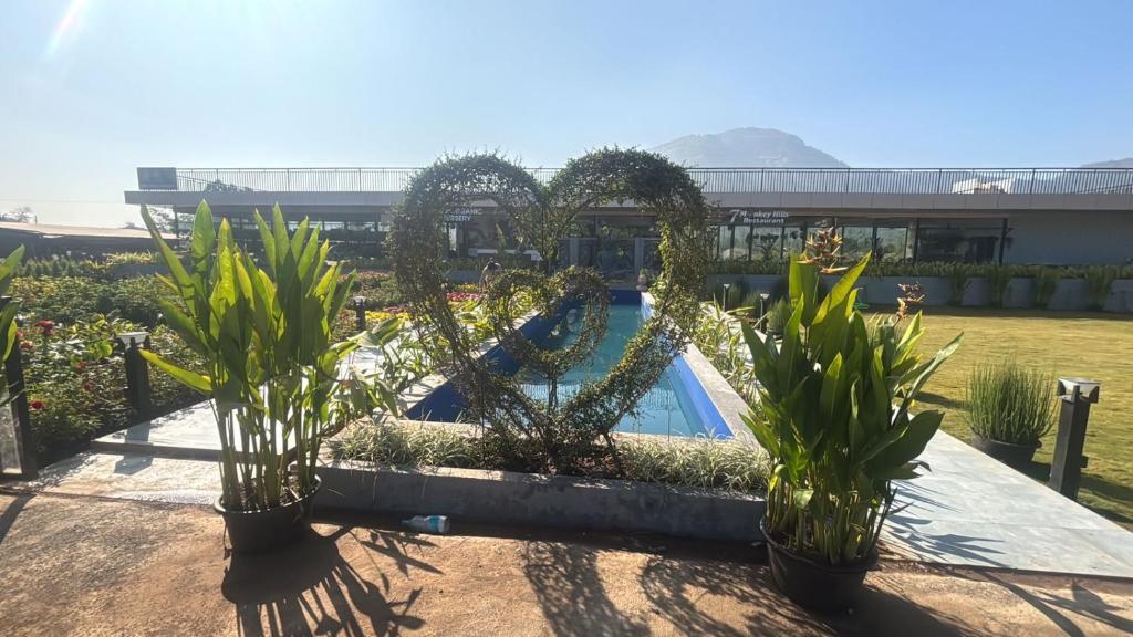 a resort with a swimming pool and potted plants at 7 Tree Resort & Restaurant in Pune
