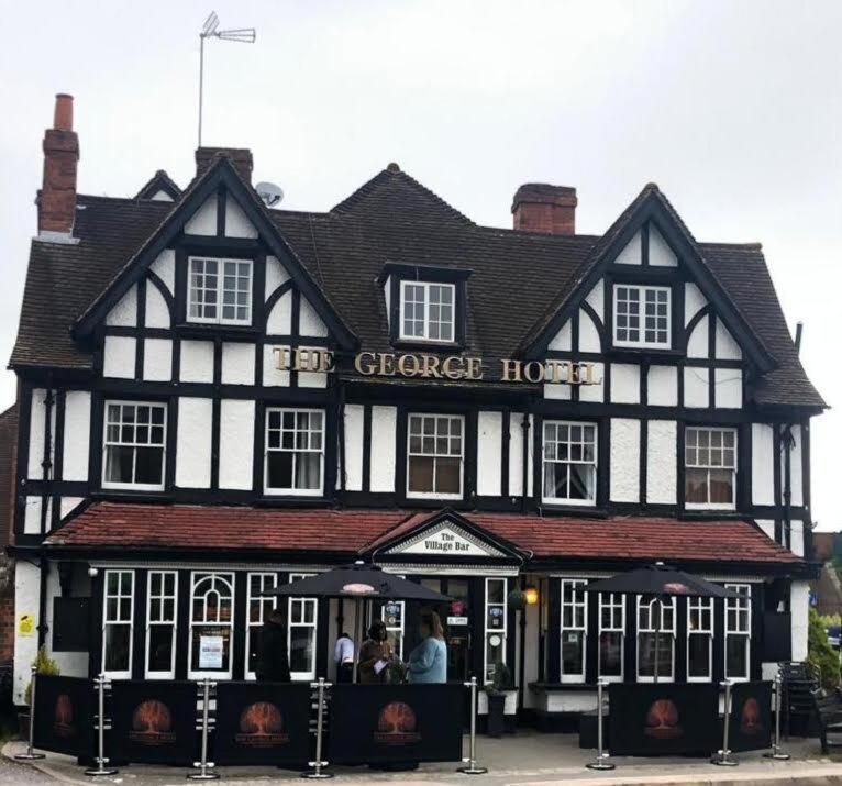 a black and white building with people standing outside of it at The George Hotel in Pangbourne