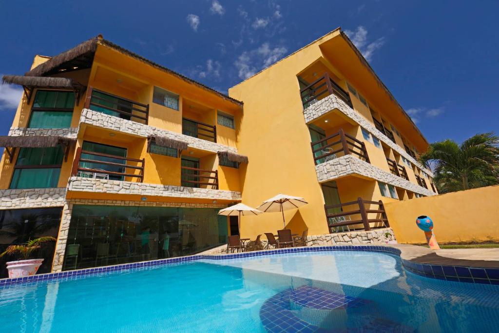 a hotel with a swimming pool in front of a building at Pousada Doce Cabana in Porto De Galinhas