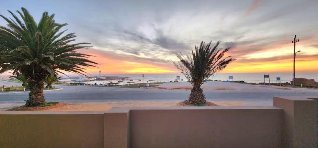 two palm trees on a beach at sunset at House Magriet in Doring Bay