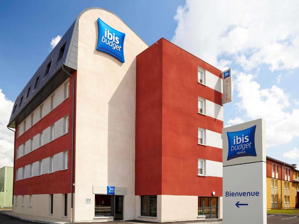 a red and white building with aubs advice sign on it at ibis budget Pontarlier in Pontarlier