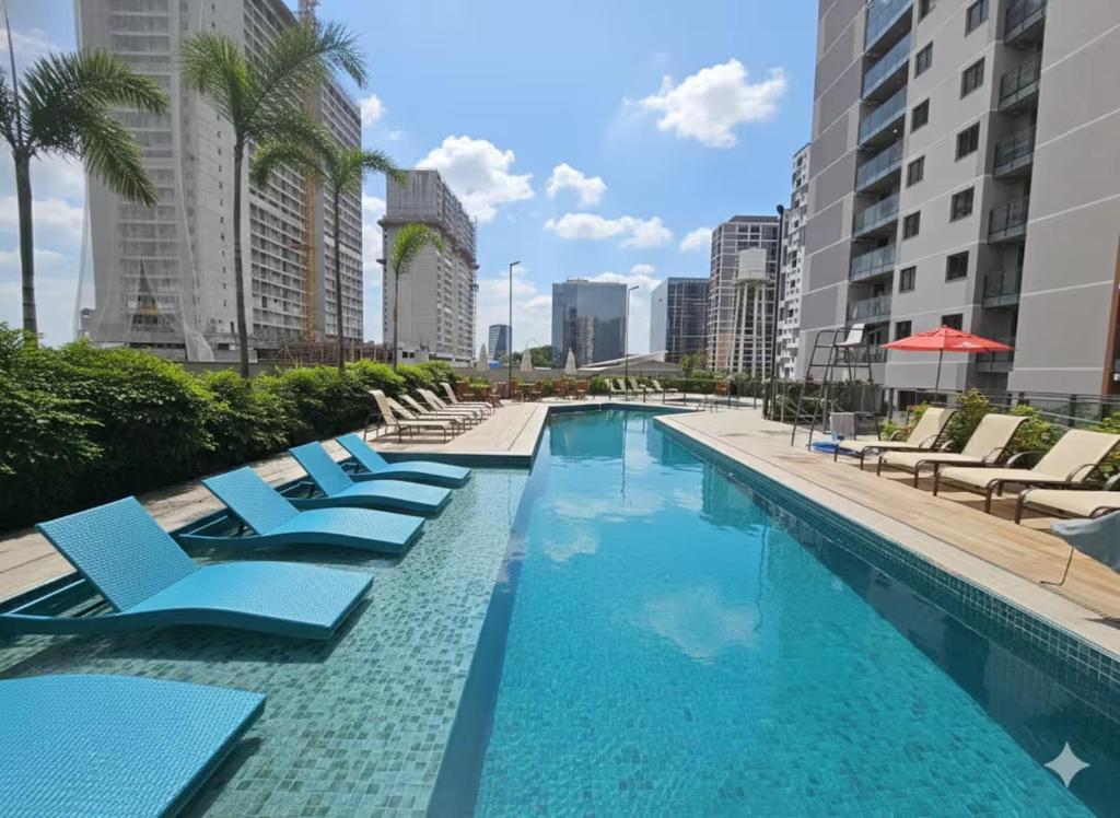 a swimming pool with blue lounge chairs and palm trees at Loft Moderno Vista Mar - 14 Minutos De Copacabana in Rio de Janeiro