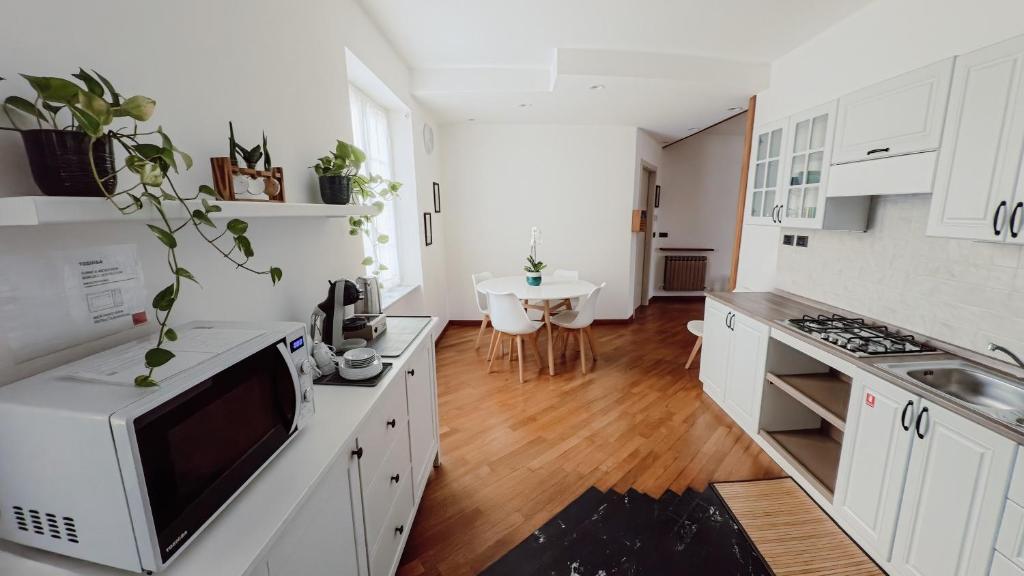 eine Küche mit weißen Schränken und einem Tisch mit Mikrowelle in der Unterkunft Ca' hygge in Lavagna