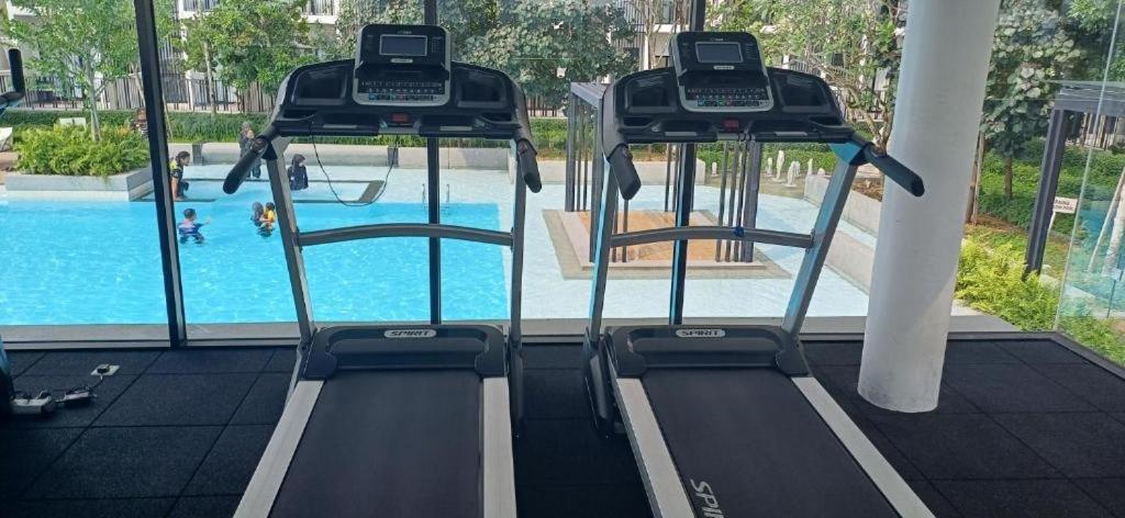 a gym with two treadmills and a swimming pool at Habitus in Shah Alam