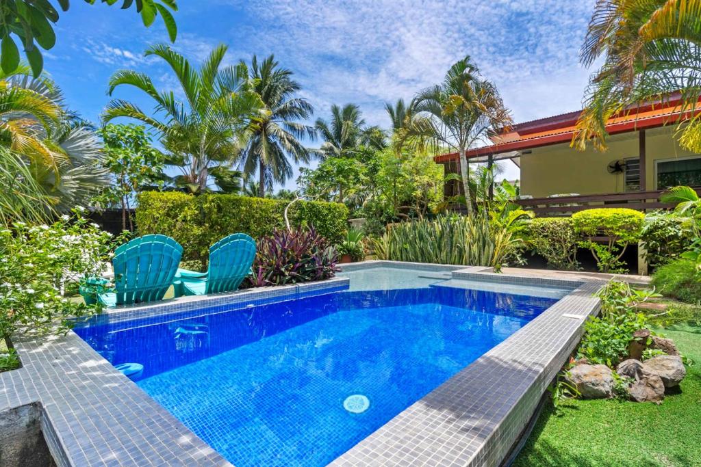 a swimming pool in a yard with chairs and a house at Modern Villa with Pool & Garden in Farehau