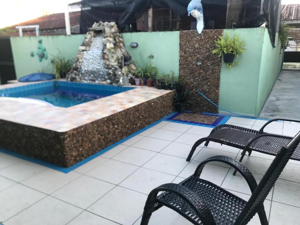 a pool with two chairs and a water fountain at Casa com piscina em Peruíbe in Peruíbe