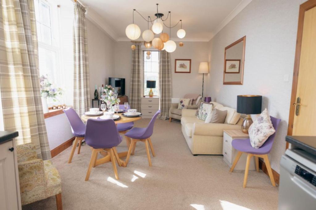 a living room with a table and purple chairs at The Nest - Chandlers in Rothesay