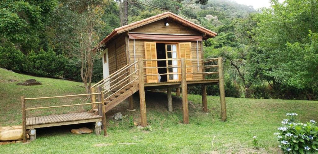 a small tree house with a porch and a bench at Pousada Recanto da Pantera in Cunha