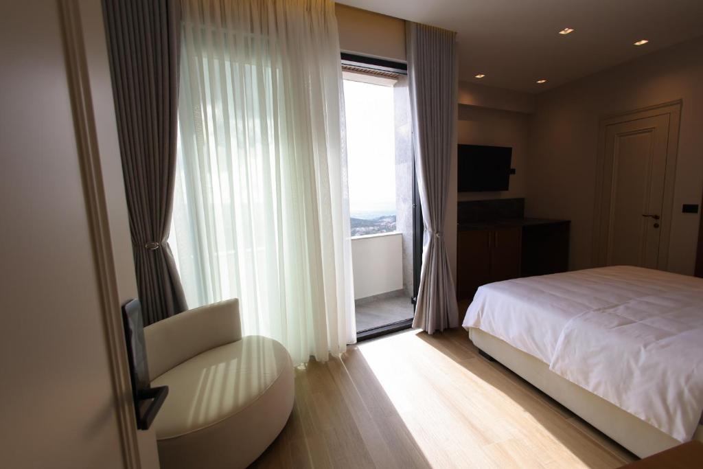 a bedroom with a bed and a chair and a window at Dion Boutique Hotel - City Center in Krujë