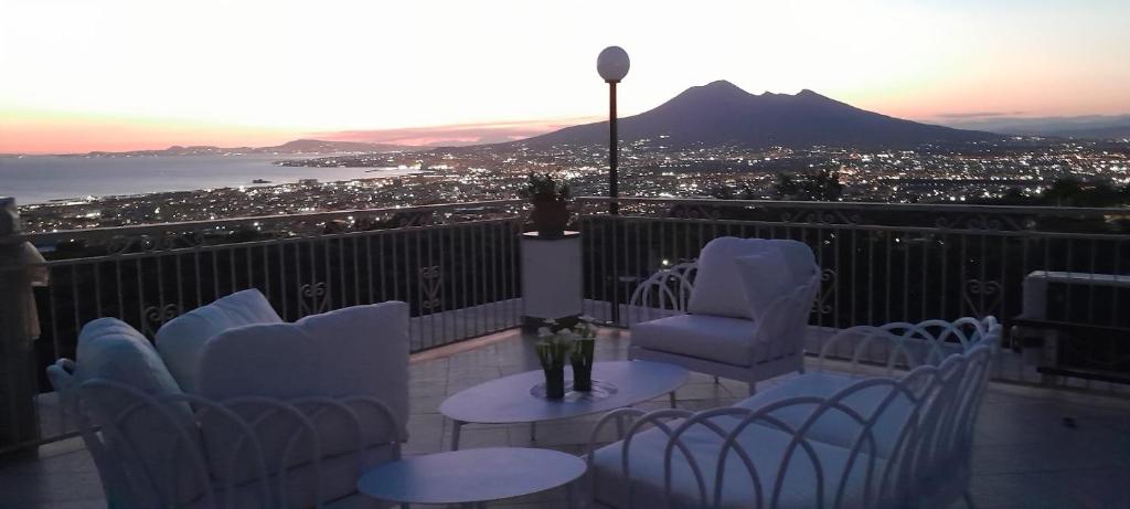 a balcony with chairs and tables and a view of a city at La Vigna del Vento in Casola di Napoli
