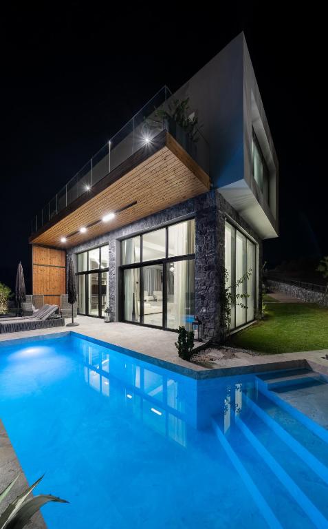 a swimming pool in front of a house at night at Alicanto K1 in Polychrono
