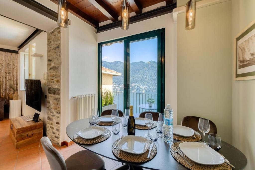 a dining room with a table and chairs and a large window at Stunning lake view, Cernobbio in Cernobbio