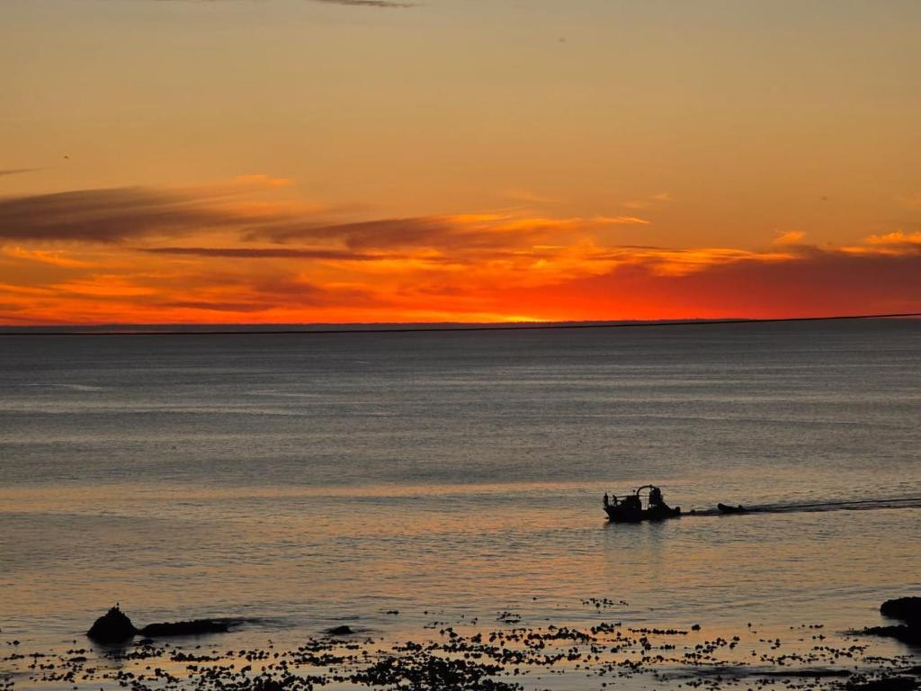 a boat in the water with a sunset in the background at Lighthouse Studio in Doring Bay