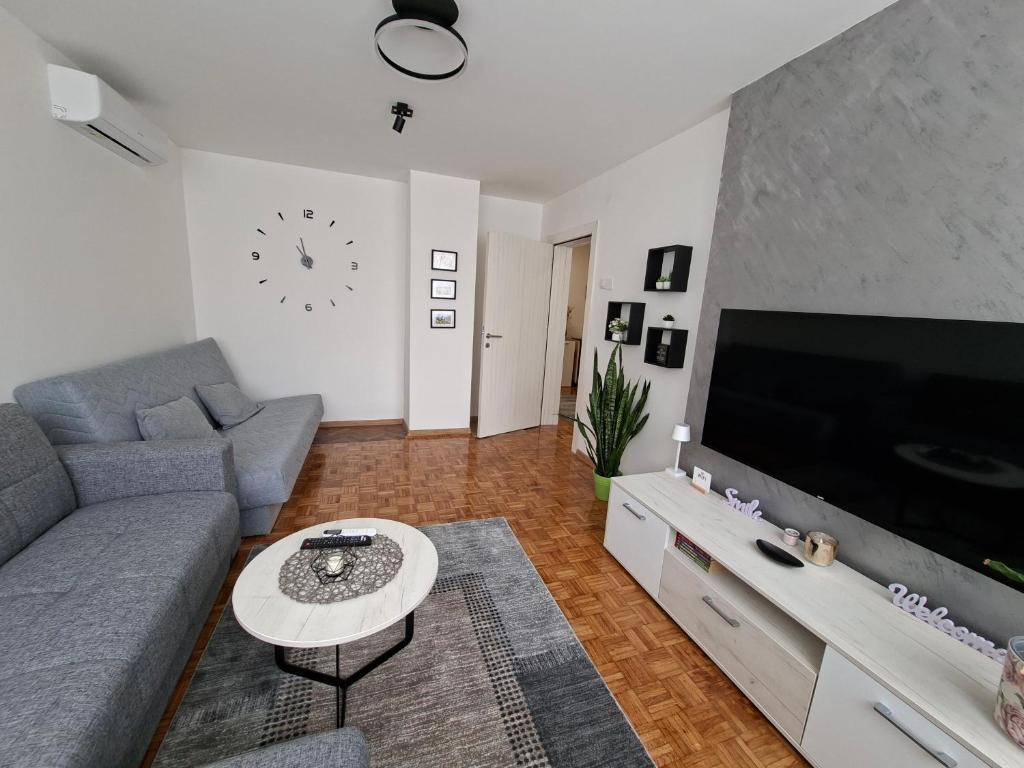 a living room with a couch and a large tv at Luna apartman in Čačak