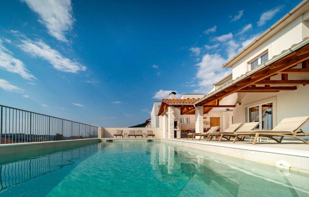 a swimming pool with chairs and a house at NEW! Villa Rabella - Luxury Oasis, Island Rab in Rab