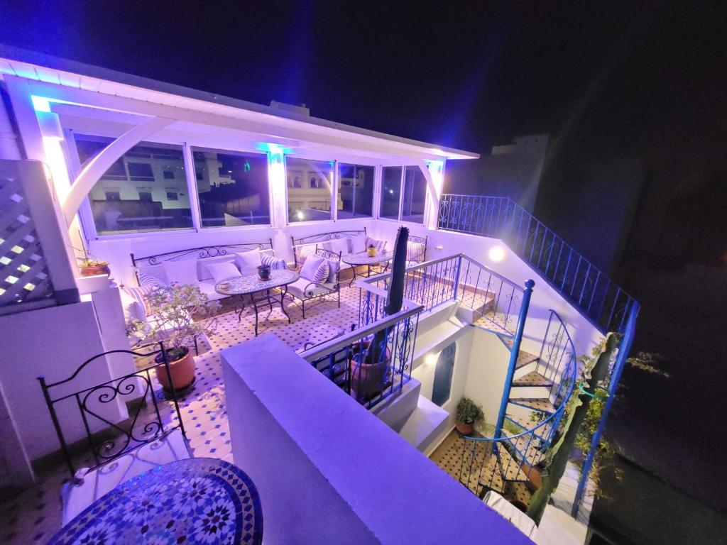 a balcony with a table and chairs on a house at night at Dar Dahbia in Asilah