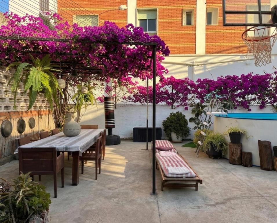 a patio with a table and a bunch of purple flowers at Villa Dimarts- a 100m de playa in Gandía