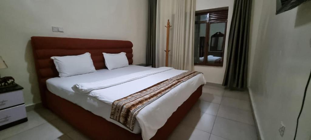 a bedroom with a large bed with a wooden headboard at Bati Valley Guest House in Kigali