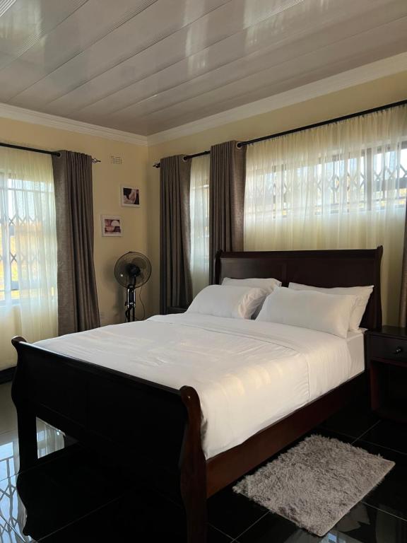 a bedroom with a large bed with white sheets at Indolo Home in Bulawayo