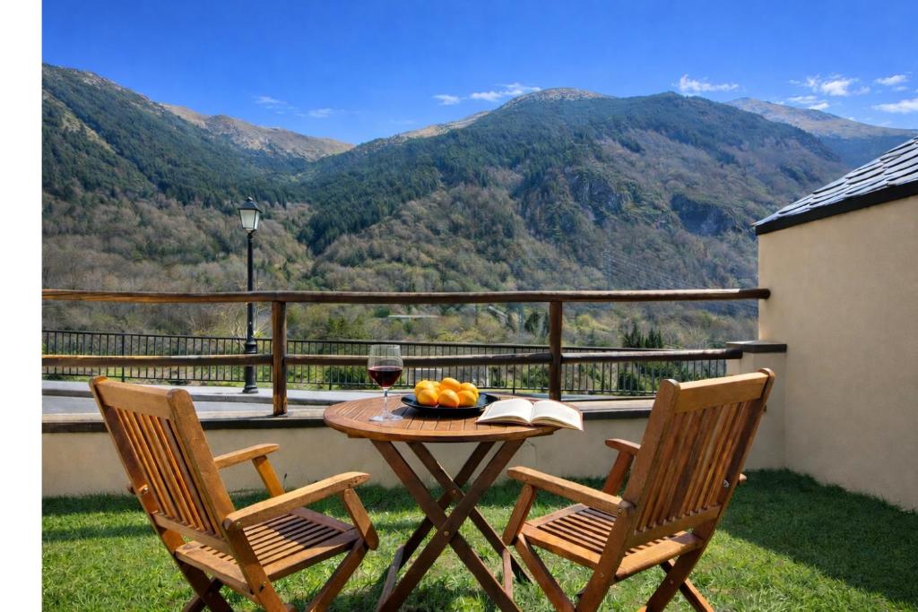 a table with a glass of wine and two chairs on a balcony at Vall Fosca Apartament Majue - Espectaculares vistas y jardín privado in Torre de Capdella
