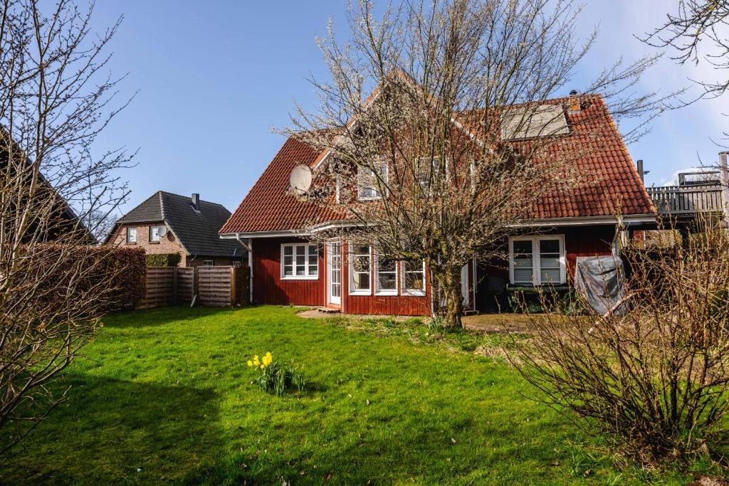 a red house with a tree in a yard at Freya in Goltoft