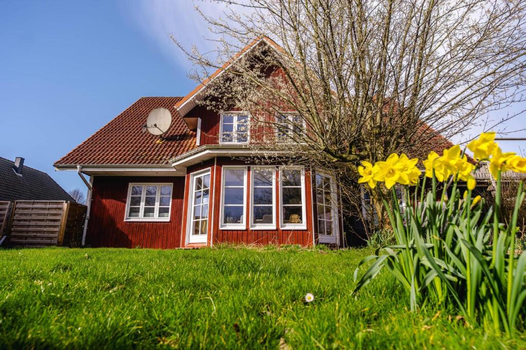 a red house with yellow flowers in the yard at Odin in Goltoft