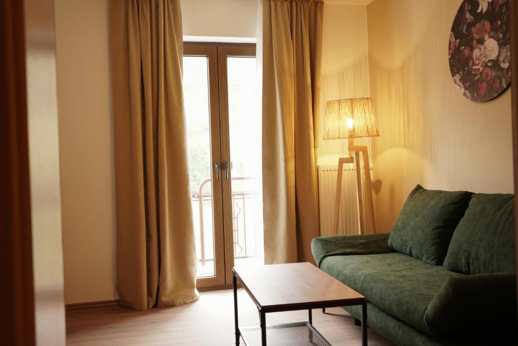 a living room with a green couch and a window at Ley Hotel in Klotten
