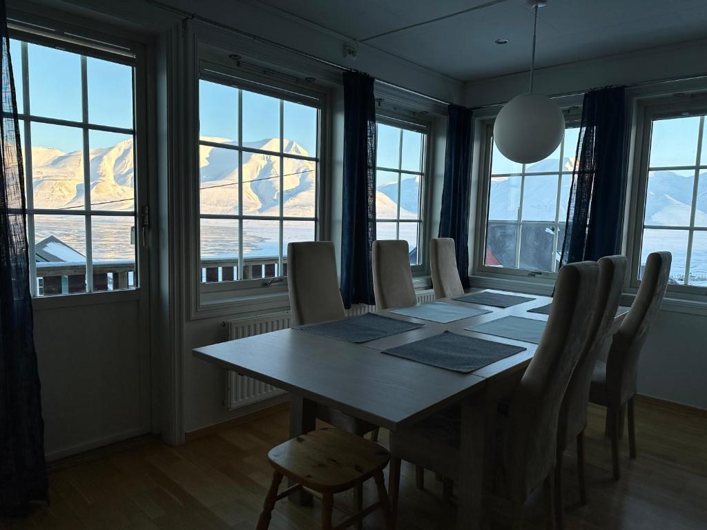 a dining room with a table and chairs and windows at Apartments with Panoramic Views in Longyearbyen