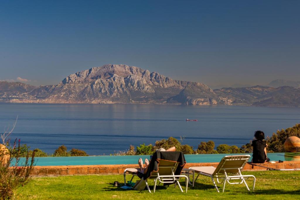 two people sitting in lawn chairs near a body of water at Cortijo La Hoya in El Bujeo