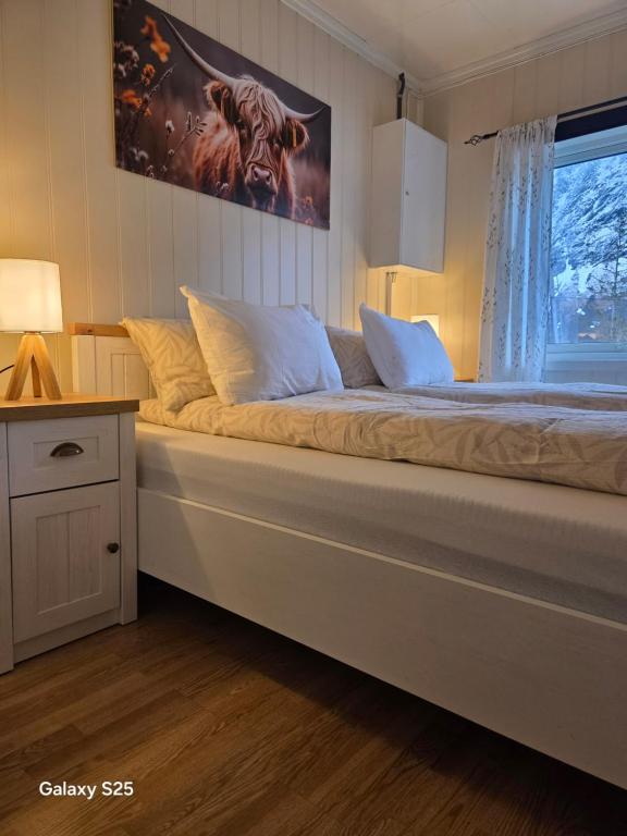 a bed with white pillows and a window in a room at Auroraheim in Gryllefjord