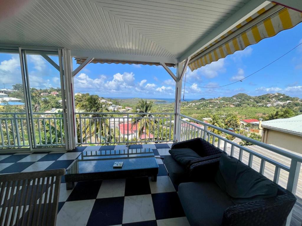 a living room with a couch and a table on a balcony at Maison Belle Vue in Le Robert