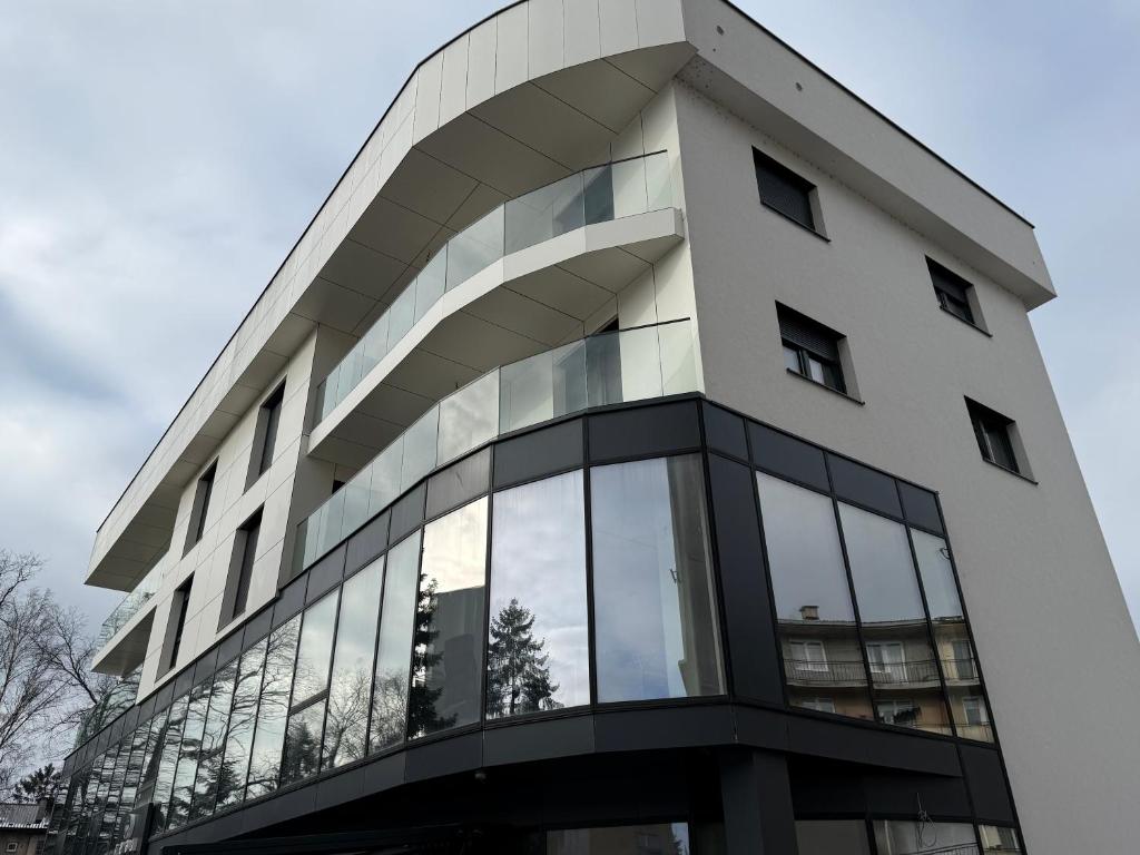 a tall white building with glass windows at Real Residence Bugojno in Bugojno