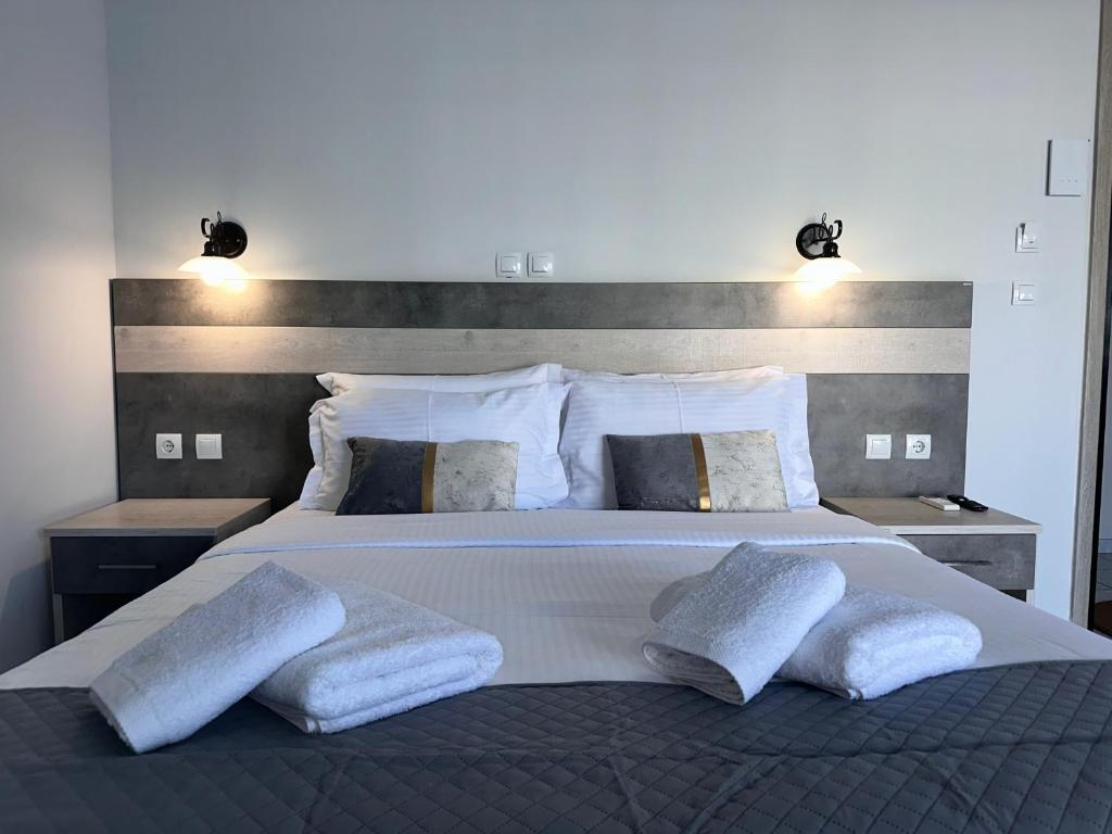 a bedroom with a large white bed with three pillows at Airport Suites Michelle in Spata